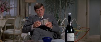 Movie still from “Escape from the Planet of the Apes” (1971), directed by Don Taylor – A man in a suit and tie sitting at a table with a book; Medium shot, Low angle