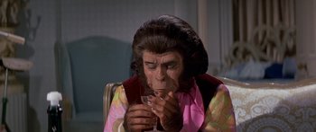 Movie still from “Escape from the Planet of the Apes” (1971), directed by Don Taylor – A woman in a pink shirt is holding a cup; Close Up shot, High angle