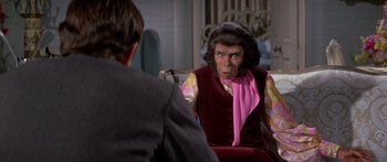 Movie still from “Escape from the Planet of the Apes” (1971), directed by Don Taylor – A man sitting in front of a woman wearing a pink scarf; Medium shot, Over the shoulder angle