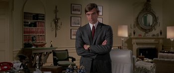 Movie still from “Escape from the Planet of the Apes” (1971), directed by Don Taylor – A man in a suit and tie standing with his arms crossed; Medium shot, Low angle