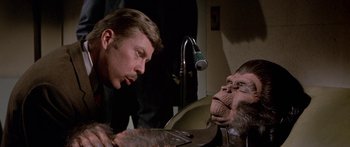 Movie still from “Escape from the Planet of the Apes” (1971), directed by Don Taylor – A man is looking at a monkey in a room; Close Up shot, Over the shoulder angle