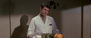 Movie still from “Escape from the Planet of the Apes” (1971), directed by Don Taylor – A man wearing a lab coat holding a tray of oranges; Medium shot, Over the shoulder angle