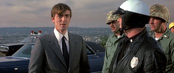 Movie still from “Escape from the Planet of the Apes” (1971), directed by Don Taylor – A man in a suit and tie standing next to two other men in military fatigues; Close Up shot, Low angle