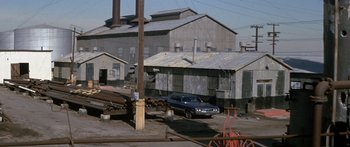 Movie still from “Escape from the Planet of the Apes” (1971), directed by Don Taylor – An old car is parked in front of an old factory; Extreme Wide shot, High angle
