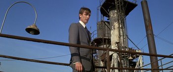 Movie still from “Escape from the Planet of the Apes” (1971), directed by Don Taylor – A man in a suit standing next to a metal fence; Medium shot, Low angle
