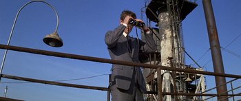 Movie still from “Escape from the Planet of the Apes” (1971), directed by Don Taylor – A man in a gray suit looking through binoculars; Medium shot, Low angle