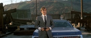 Movie still from “Escape from the Planet of the Apes” (1971), directed by Don Taylor – A man in a suit and tie standing next to a car; Medium shot, Low angle