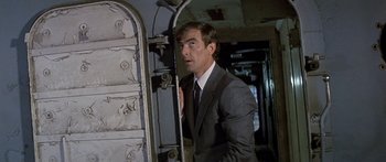 Movie still from “Escape from the Planet of the Apes” (1971), directed by Don Taylor – A man wearing a suit and tie standing in front of a door; Medium shot, Low angle