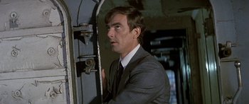 Movie still from “Escape from the Planet of the Apes” (1971), directed by Don Taylor – A man wearing a suit and tie standing in front of a door; Close Up shot, Low angle