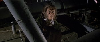 Movie still from “Escape from the Planet of the Apes” (1971), directed by Don Taylor – A man with a gorilla mask and a green shirt; Close Up shot, High angle
