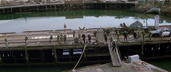 Movie still from “Escape from the Planet of the Apes” (1971), directed by Don Taylor – A group of people standing on a dock next to a body of water; Extreme Wide shot, High angle