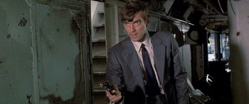 Movie still from “Escape from the Planet of the Apes” (1971), directed by Don Taylor – A man in a suit holding a gun in his hand; Close Up shot, Low angle