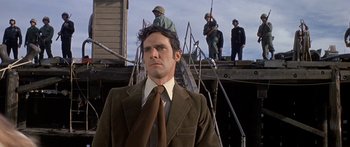 Movie still from “Escape from the Planet of the Apes” (1971), directed by Don Taylor – A man wearing a suit and tie standing on a wooden platform; Medium shot, Low angle