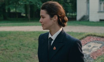 Movie still from “Europa Europa” (1990), directed by Agnieszka Holland – A woman in a suit and tie standing in a field; Close Up shot, Over the shoulder angle