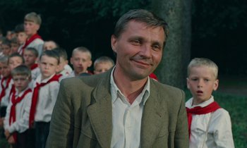Movie still from “Europa Europa” (1990), directed by Agnieszka Holland – A person wearing a suit near a group of people; Close Up shot, Low angle