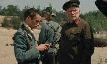 Movie still from “Europa Europa” (1990), directed by Agnieszka Holland – Two men in military uniforms looking at a cell phone; Medium shot, Over the shoulder angle