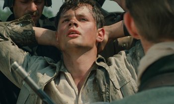 Movie still from “Europa Europa” (1990), directed by Agnieszka Holland – A young man is sitting in the middle of a group of men; Close Up shot, Low angle