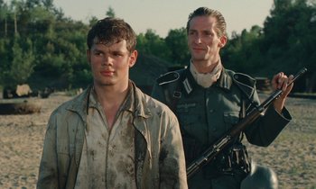 Movie still from “Europa Europa” (1990), directed by Agnieszka Holland – Two men are standing next to each other holding guns; Medium shot, Low angle