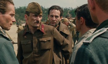 Movie still from “Europa Europa” (1990), directed by Agnieszka Holland – A group of men standing next to each other on top of a field; Medium shot, Over the shoulder angle