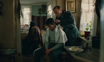 Movie still from “Europa Europa” (1990), directed by Agnieszka Holland – A man getting his hair cut by another man; Medium shot, Over the shoulder angle