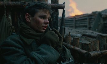 Movie still from “Europa Europa” (1990), directed by Agnieszka Holland – A young man in military fatigues sitting next to a fire; Close Up shot, High angle