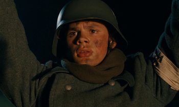 Movie still from “Europa Europa” (1990), directed by Agnieszka Holland – A young man in a military uniform wearing a hat and a scarf; Close Up shot, Low angle