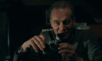 Movie still from “Europa Europa” (1990), directed by Agnieszka Holland – A man holding an old camera in his hands; Close Up shot, Low angle