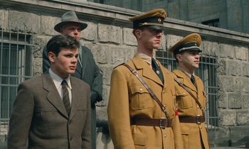 Movie still from “Europa Europa” (1990), directed by Agnieszka Holland – A group of men standing next to each other wearing suits; Medium shot, Low angle