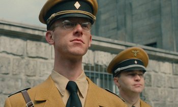 Movie still from “Europa Europa” (1990), directed by Agnieszka Holland – Two men in military uniforms are standing next to each other in front of a building; Close Up shot, Low angle