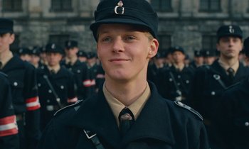 Movie still from “Europa Europa” (1990), directed by Agnieszka Holland – A young man in a military uniform stands in front of a group of soldiers; Close Up shot, Low angle