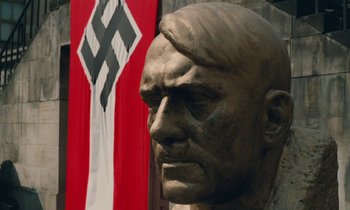 A statue of a man in front of a nazi flag