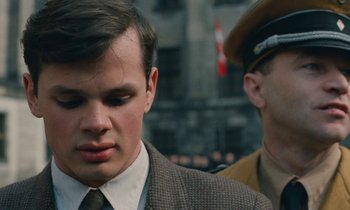 Movie still from “Europa Europa” (1990), directed by Agnieszka Holland – A man in a suit and tie next to another man in a hat; Close Up shot, Over the shoulder angle