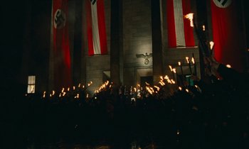 Movie still from “Europa Europa” (1990), directed by Agnieszka Holland – A group of people holding torches in front of a building; Extreme Wide shot, High angle