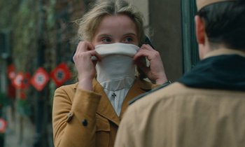 Movie still from “Europa Europa” (1990), directed by Agnieszka Holland – A young woman wearing a face mask while talking on a cell phone; Close Up shot, Over the shoulder angle