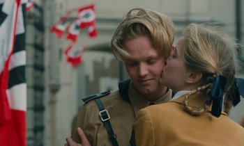 Movie still from “Europa Europa” (1990), directed by Agnieszka Holland – A man and a woman kissing in front of a flag; Close Up shot, Low angle