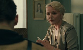 Movie still from “Europa Europa” (1990), directed by Agnieszka Holland – A woman sitting in front of a man holding a cell phone; Close Up shot, Over the shoulder angle