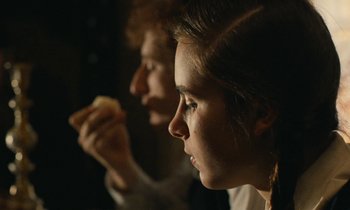 Movie still from “Europa Europa” (1990), directed by Agnieszka Holland – Two people sitting side - by - side eating a sandwich; Close Up shot, Over the shoulder angle