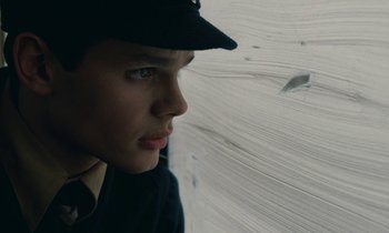 Movie still from “Europa Europa” (1990), directed by Agnieszka Holland – A young man wearing a hat looking out of a window; Close Up shot, Low angle