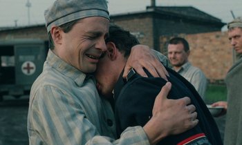 Movie still from “Europa Europa” (1990), directed by Agnieszka Holland – Two men are hugging each other in a prison yard; Close Up shot, Over the shoulder angle