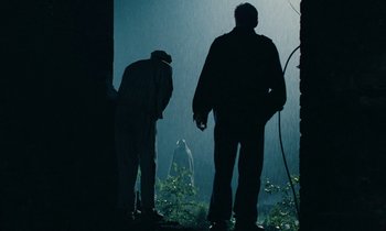 Movie still from “Europa Europa” (1990), directed by Agnieszka Holland – Two men standing in the rain looking at a statue; Wide shot, Low angle