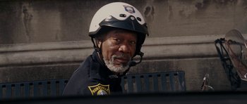 Movie still from “Evan Almighty” (2007), directed by Tom Shadyac – A man in a police uniform sitting on top of a park bench; Close Up shot, Over the shoulder angle