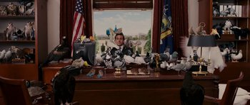 Movie still from “Evan Almighty” (2007), directed by Tom Shadyac – A man sitting at a desk with a lot of stuffed animals on it; Medium shot, Low angle