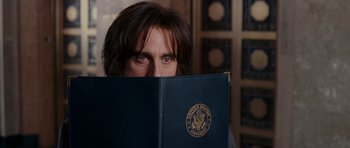 Movie still from “Evan Almighty” (2007), directed by Tom Shadyac – A man holding a book in front of his face; Close Up shot, Over the shoulder angle