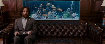 Movie still from “Evan Almighty” (2007), directed by Tom Shadyac – A man sitting on a couch in front of a fish tank; Wide shot, Over the shoulder angle