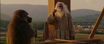 Movie still from “Evan Almighty” (2007), directed by Tom Shadyac – An old man with long white hair is drinking from a cup; Medium shot, Over the shoulder angle