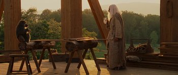 Movie still from “Evan Almighty” (2007), directed by Tom Shadyac – An old man dressed as a wizard standing next to a table; Wide shot, Over the shoulder angle