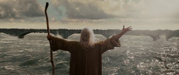 Movie still from “Evan Almighty” (2007), directed by Tom Shadyac – A man standing on a boat with his arms outstretched in the water; Medium shot, Low angle