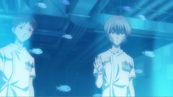 Movie still from “Evangelion: 2.0 You Can (Not) Advance” (2009), directed by Joe Fria – A man standing in front of some fish in a room; Medium shot, Low angle