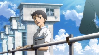 Movie still from “Evangelion: 2.0 You Can (Not) Advance” (2009), directed by Joe Fria – A man standing next to a railing in front of a building; Medium shot, Low angle