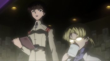 Movie still from “Evangelion: 2.0 You Can (Not) Advance” (2009), directed by Joe Fria – Two people are standing next to each other in a dark room; Medium shot, Low angle